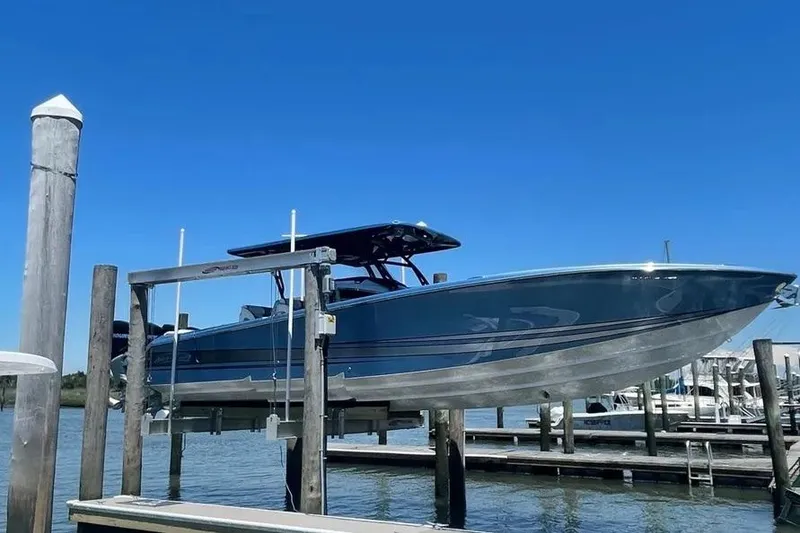 Slide: The Image of 2021 Nor-Tech 390 Sport Center Console boat on lift, clear blue sky background. - 4