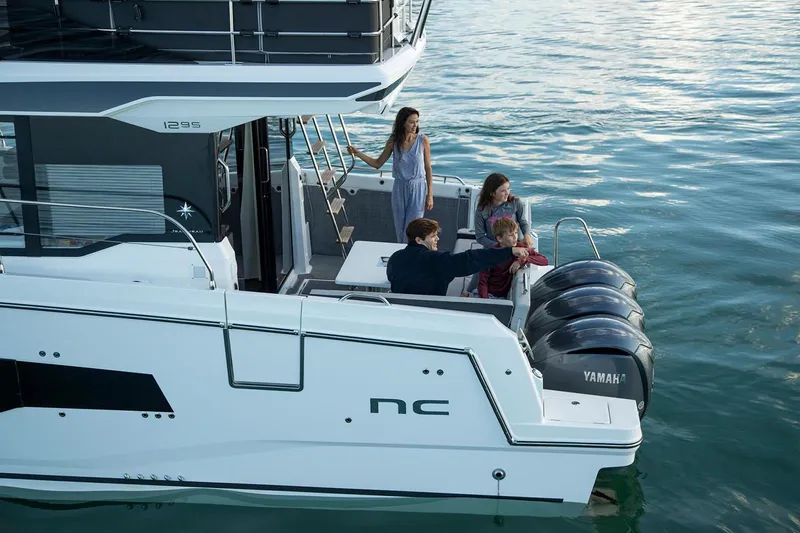 Slide: The Image of 2024 Jeanneau NC 1295 Fly yacht deck with seating, table, and ladder. - 11