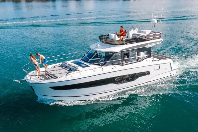 Slide: The Image of 2024 Jeanneau NC 1295 Fly yacht docked by a scenic waterfront. - 2