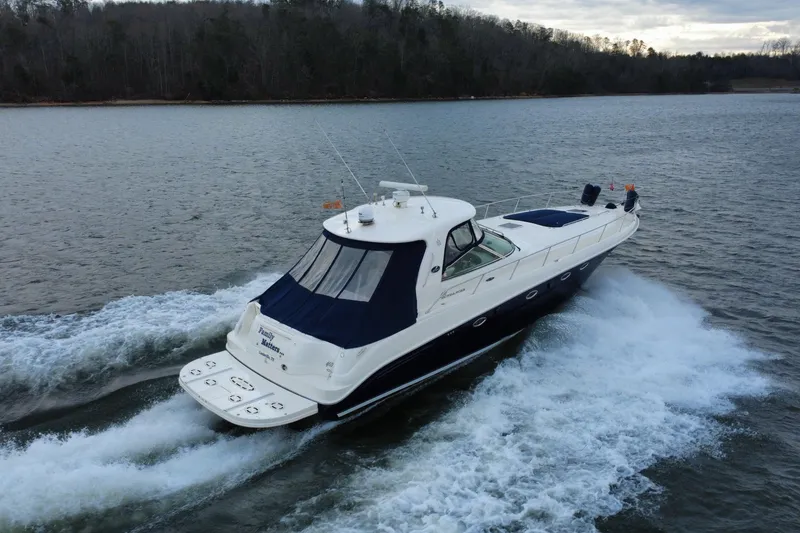 Slide: The Image of 2004 Sea Ray Sundancer 460 cruising on a serene lake with forested shoreline. - 12
