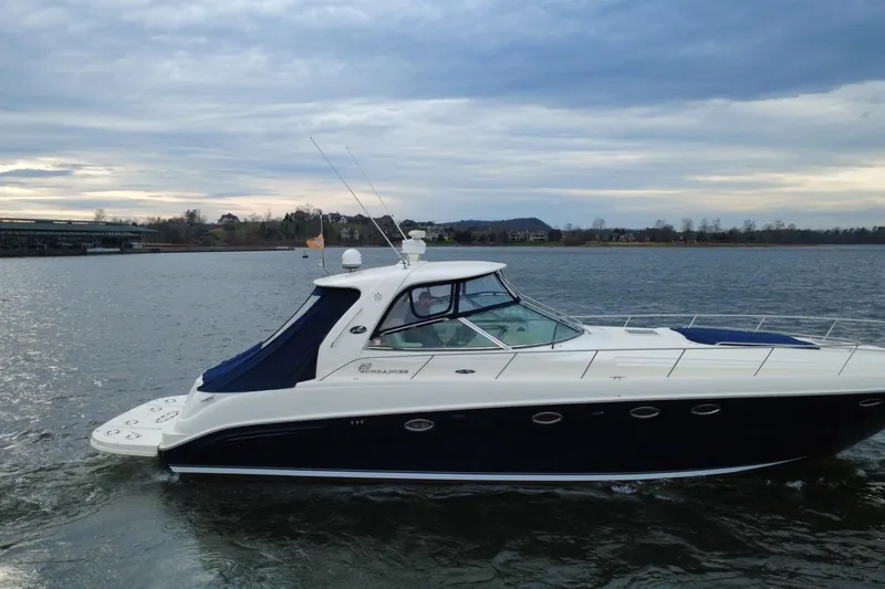 Slide: The Image of 2004 Sea Ray Sundancer 460 yacht cruising on a serene lake under a cloudy sky. - 3