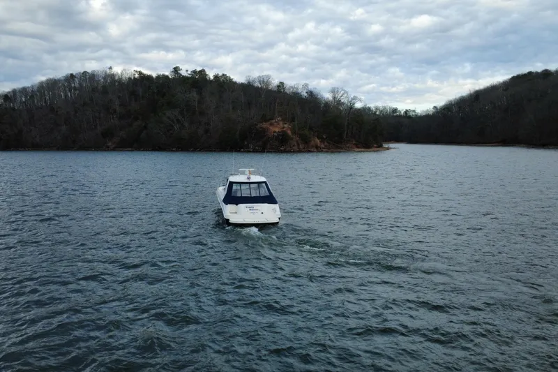 Slide: The Image of Sea Ray Sundancer 460 (2004) cruising on a serene lake with wooded shoreline. - 6