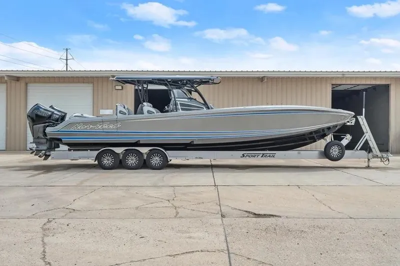 Slide: The Image of 2023 Nor-Tech 390 Sport Center Console boat on trailer, parked outside a warehouse. - 3