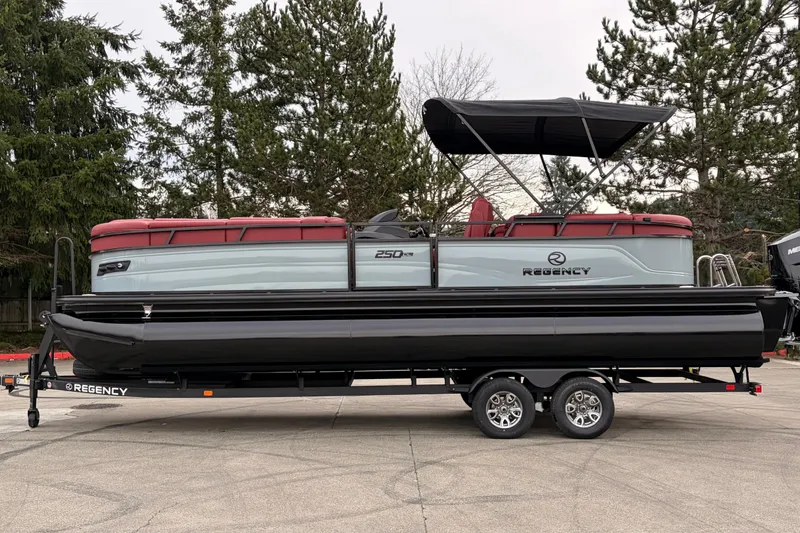 The Image of 2026 Regency 250 DL pontoon boat on trailer, featuring sleek design and red seating. - 0