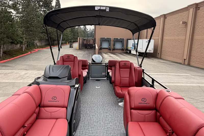 Slide: The Image of 2026 Regency 250 DL pontoon boat with red seating and canopy in a parking area. - 7