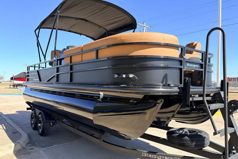 Slide: The Image of 2026 Ranger 223FC pontoon boat with tan seating and black exterior on trailer. - 4