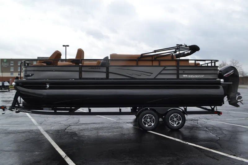 The Image of 2026 Ranger 223FC pontoon boat on trailer in parking lot, overcast sky. - 0