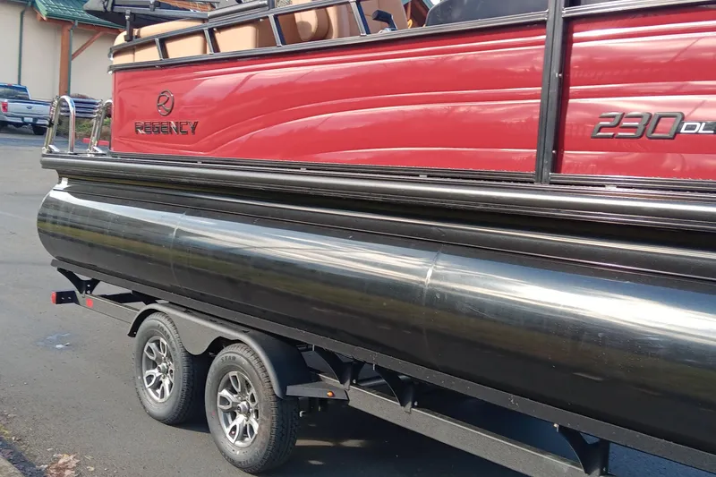 Slide: The Image of 2026 Regency 230 DL pontoon boat on trailer, red and black design. - 2