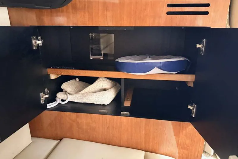 Slide: The Image of Open cabinet in 2007 Sea Ray 340 Sundancer boat, showing storage with rope and cushion. - 26