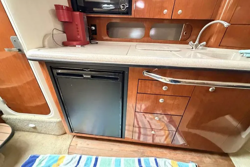 Slide: The Image of 2007 Sea Ray 340 Sundancer galley with wood cabinetry, mini fridge, and sink. - 33