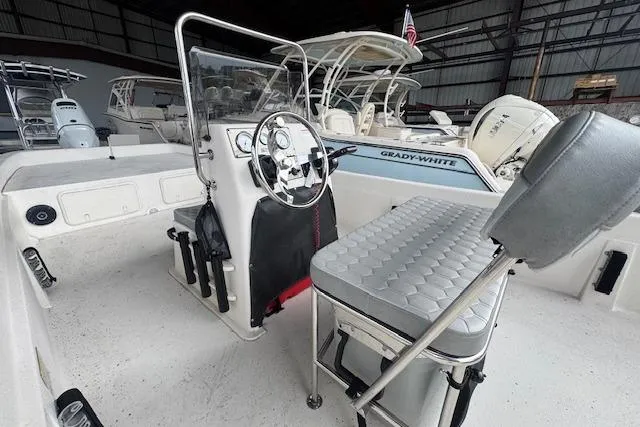 Slide: The Image of 2026 Carolina Skiff E24 DLX CC boat interior with steering console and seating in a showroom. - 10