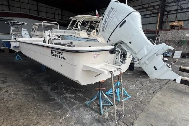 Slide: The Image of 2026 Carolina Skiff E24 DLX CC boat with Suzuki outboard motor in a warehouse. - 6
