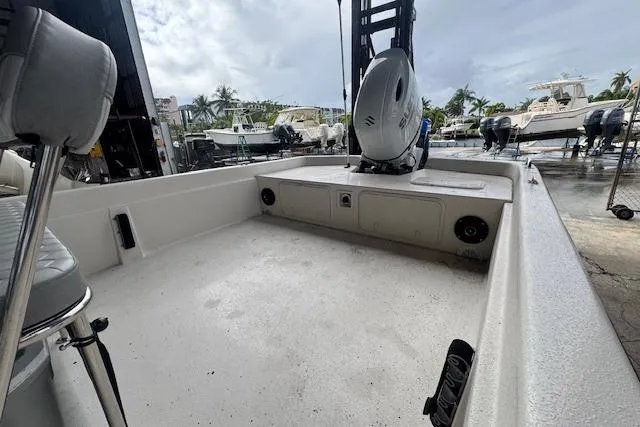 Slide: The Image of 2026 Carolina Skiff E24 DLX CC boat interior with motor, docked under cloudy sky. - 8