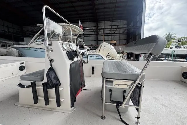 Slide: The Image of 2026 Carolina Skiff E24 DLX CC boat interior with console and seating in a marina. - 9