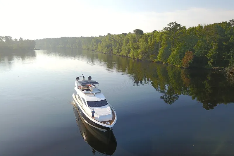 Slide: The Image of 2005 Sunseeker 75 Yacht cruising on a serene river surrounded by lush greenery. - 2
