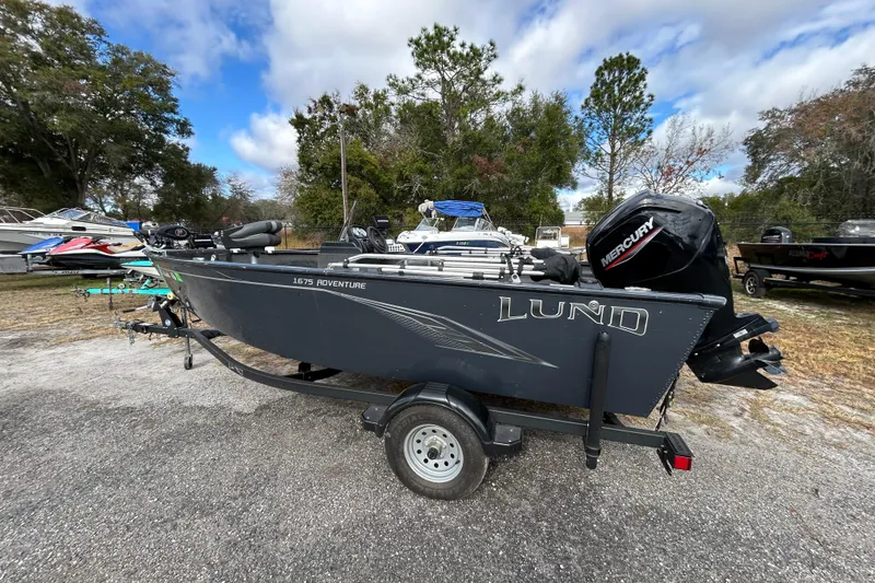 The Image of 2021 Lund 1675 Adventure SS boat with Mercury engine on trailer, parked outdoors. - 1