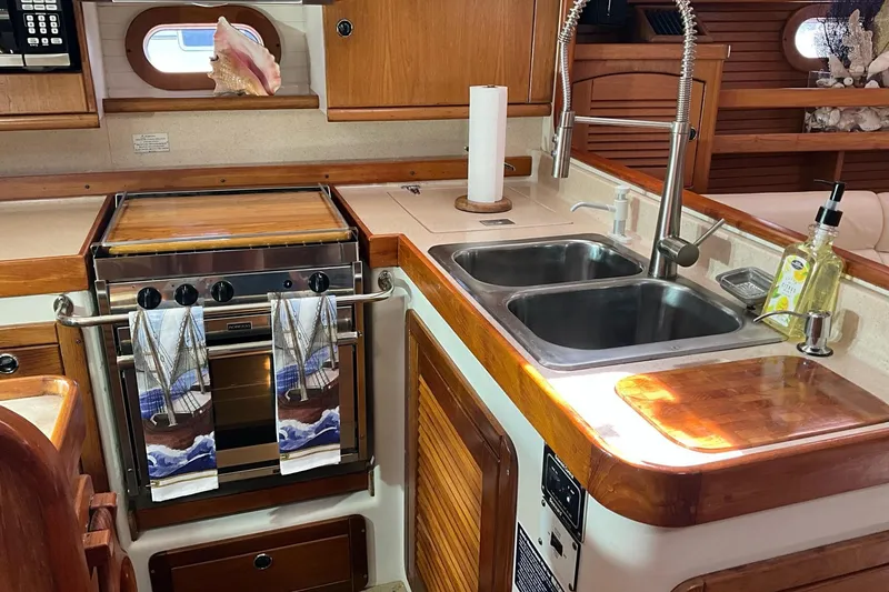 Slide: The Image of Interior of 2000 Catalina 470 yacht kitchen with stove, sink, and wooden cabinetry. - 11