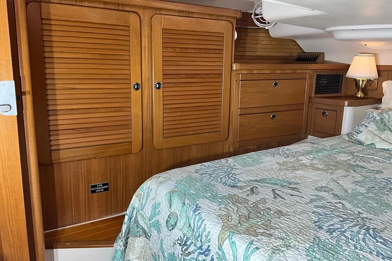 Slide: The Image of Cozy cabin interior of 2000 Catalina 470 sailboat with wooden cabinetry and patterned bedding. - 16