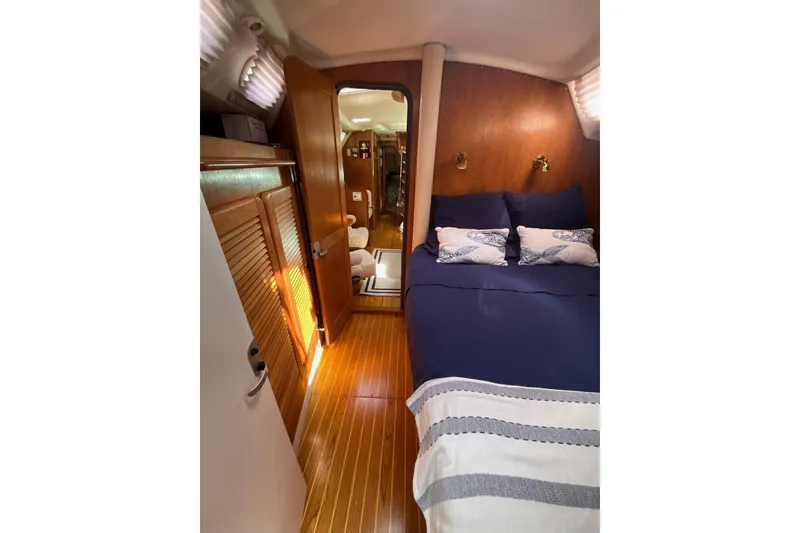 Slide: The Image of Cozy interior of 2000 Catalina 470 yacht with wooden finishes and blue bedding. - 18