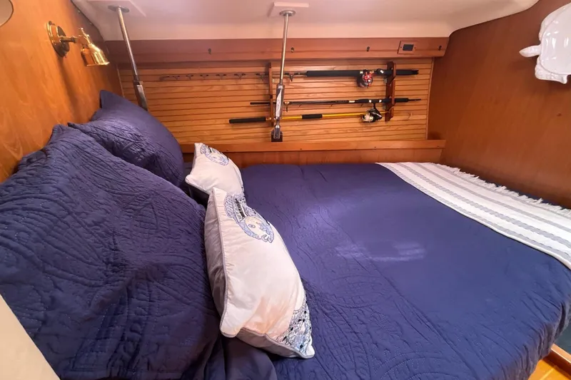 Slide: The Image of Cozy cabin interior of 2000 Catalina 470 yacht with blue bedding and fishing rods. - 19