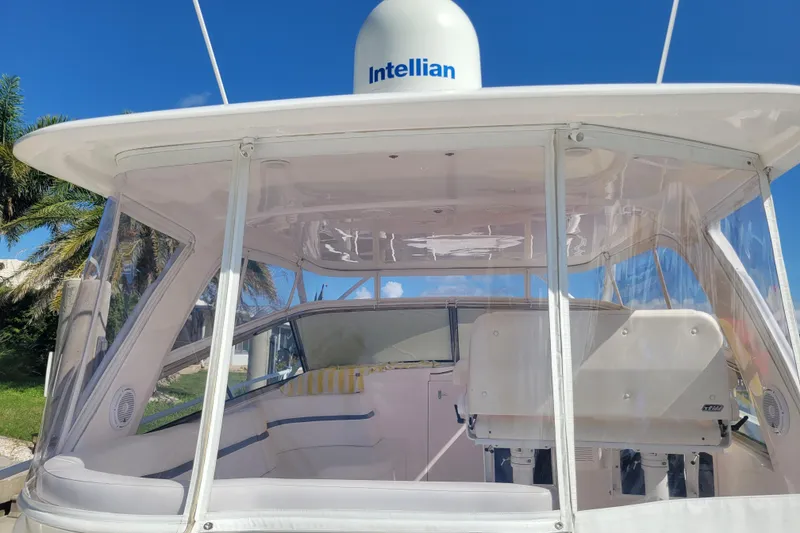 Slide: The Image of 2016 Intrepid 475 Sport Yacht cockpit with clear enclosure and seating, under blue sky. - 4