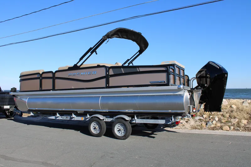 Slide: The Image of 2026 Premier 230 Sunsation Angler 2pt pontoon boat on trailer by the sea. - 1
