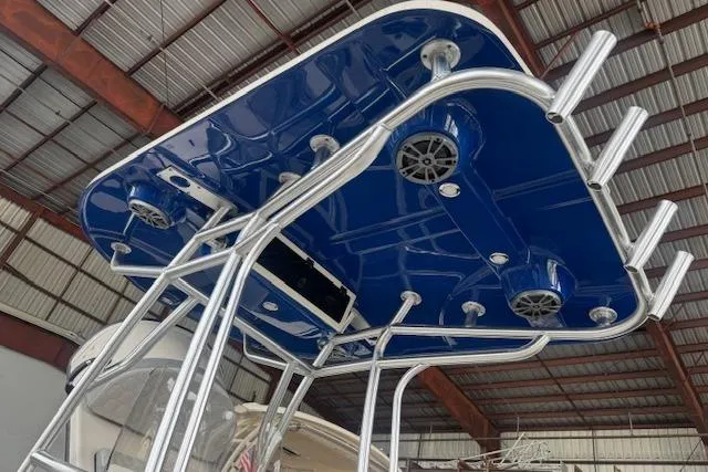 Slide: The Image of 2026 Carolina Skiff 25 LS boat with blue T-top and rod holders in a warehouse. - 9