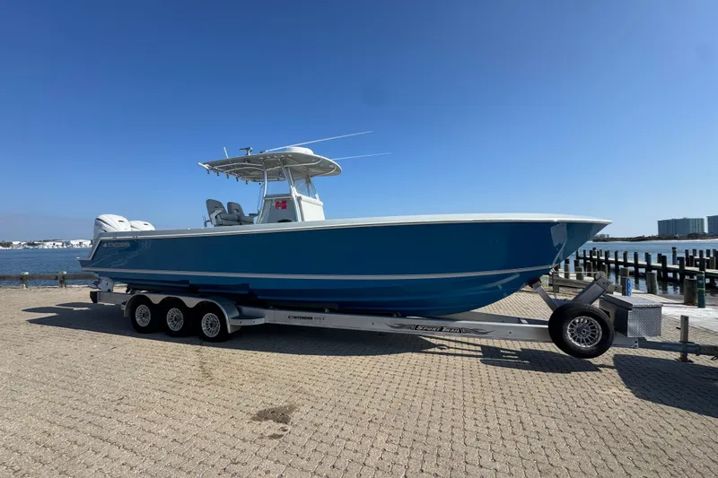 The Image of 2016 Contender 35 ST boat on trailer by waterfront, clear blue sky. - 1