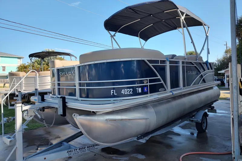 Slide: The Image of 2023 Sylvan Mirage 8520 Party Fish pontoon boat on trailer, blue and silver design. - 2