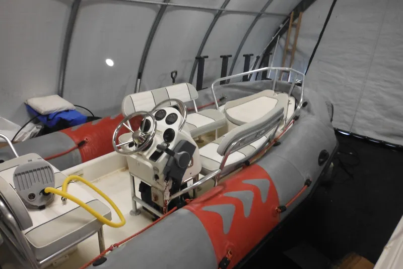 The Image of 2014 Zodiac Pro 550 inflatable boat in storage, featuring steering console and seating. - 1