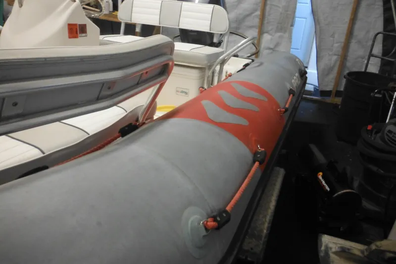Slide: The Image of 2014 Zodiac Pro 550 inflatable boat in storage, featuring red and gray design. - 11