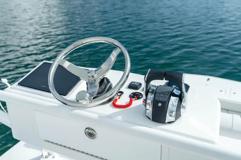 Slide: The Image of Helm of 2026 Invincible 38 Catamaran with steering wheel and controls, on calm water. - 18