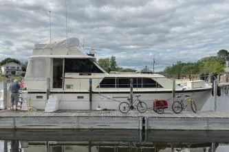 The Image of 1977 Hatteras 43 Double Cabin yacht docked with bicycles nearby under cloudy skies. - 1
