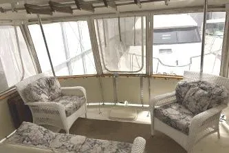 Slide: The Image of 1977 Hatteras 43 Double Cabin interior with wicker chairs and floral cushions. - 6