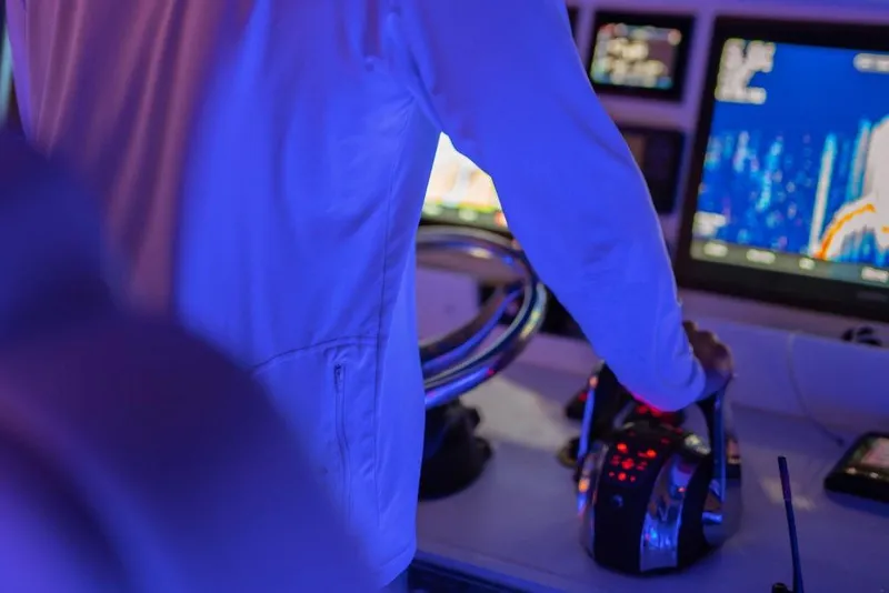 Slide: The Image of Person operating controls on Invincible 40 Catamaran, 2026 model, with illuminated dashboard. - 14