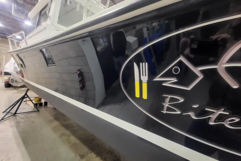 Slide: The Image of 2020 Steiger Craft 31 Miami boat with fish logo and utensils graphic in a warehouse. - 9