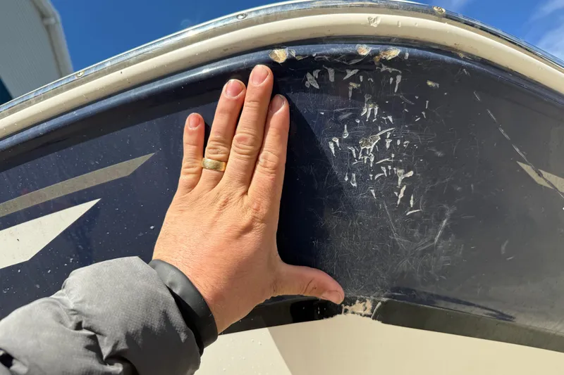 Slide: The Image of Hand inspecting scratches on 2015 Hurricane SunDeck 2000 OB boat hull. - 14