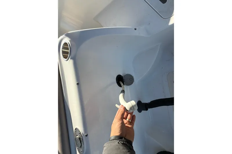 Slide: The Image of 2015 Hurricane SunDeck 2000 OB boat interior with hand holding a hose attachment. - 19