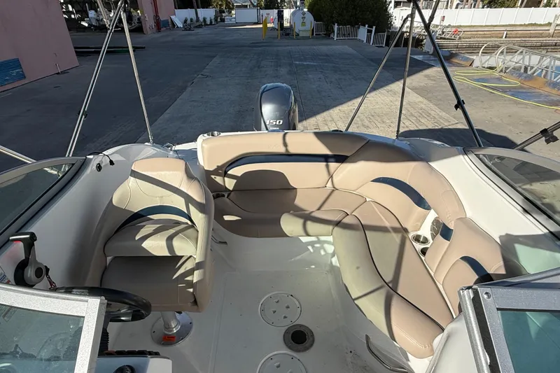Slide: The Image of 2015 Hurricane SunDeck 2000 OB boat interior with beige seating and steering wheel. - 21