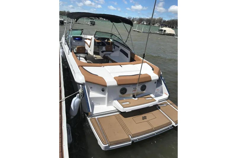 Slide: The Image of 2018 Four Winns H260 boat with tan seating and swim platform, docked on a sunny day. - 2