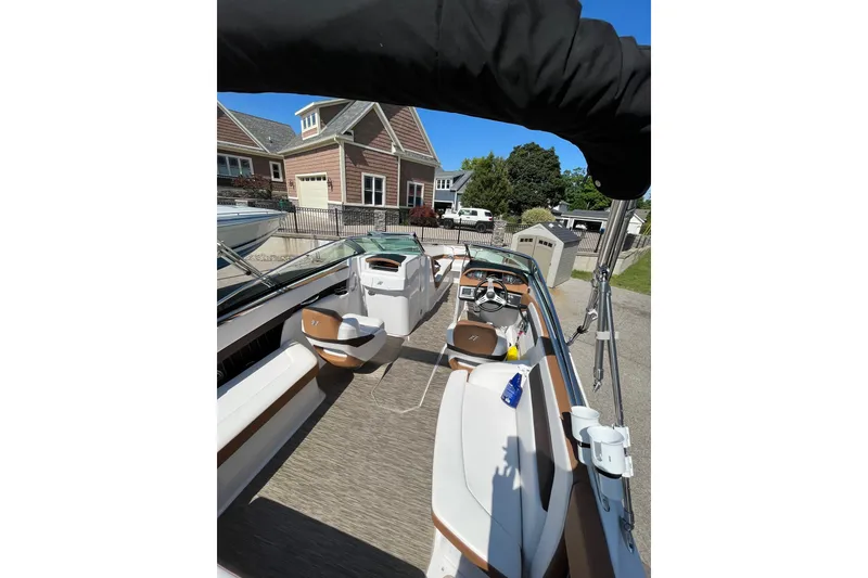 Slide: The Image of 2018 Four Winns H260 boat interior with seating and steering wheel, parked near houses. - 5