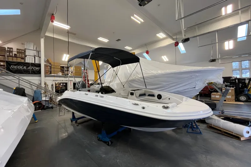 The Image of 2026 Hurricane SunDeck Sport 185 OB boat in showroom, featuring sleek design and canopy. - 0