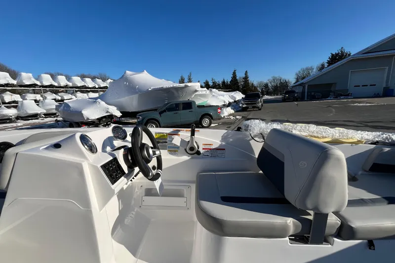 Slide: The Image of 2026 Hurricane SunDeck Sport 185 OB boat interior with steering wheel and seating, parked outdoors. - 11