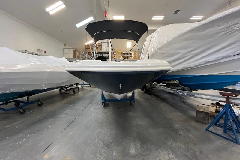Slide: The Image of 2026 Hurricane SunDeck Sport 185 OB boat in storage, surrounded by covered vessels. - 2