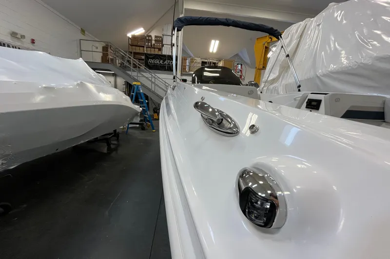 Slide: The Image of 2026 Hurricane SunDeck Sport 185 OB boat in showroom, sleek white design, indoor lighting. - 22