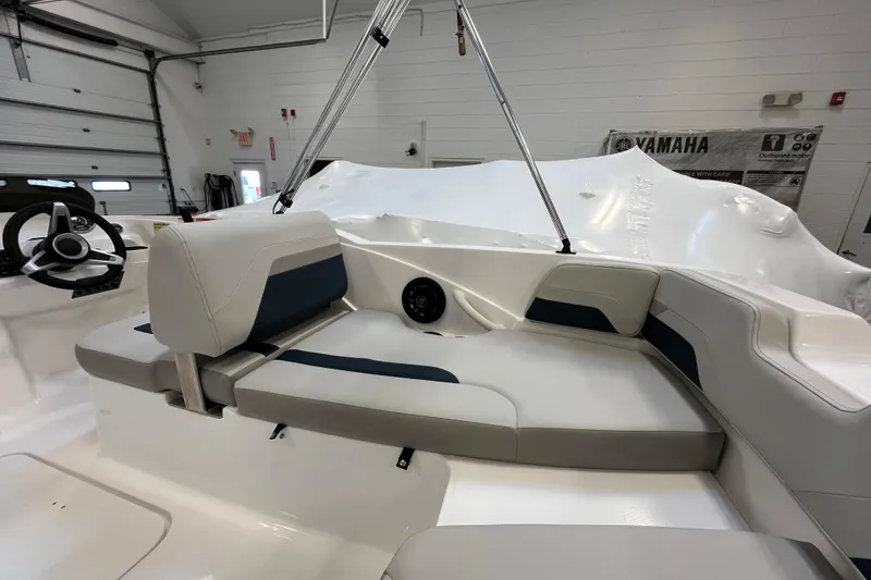 Slide: The Image of 2026 Hurricane SunDeck Sport 185 OB interior with seating and steering wheel in a showroom. - 26