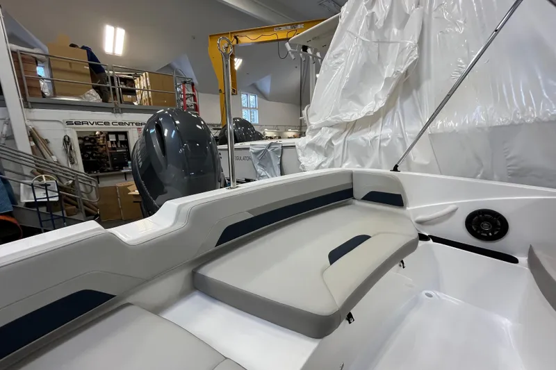 Slide: The Image of 2026 Hurricane SunDeck Sport 185 OB boat interior in a service center, showcasing seating and motor. - 27