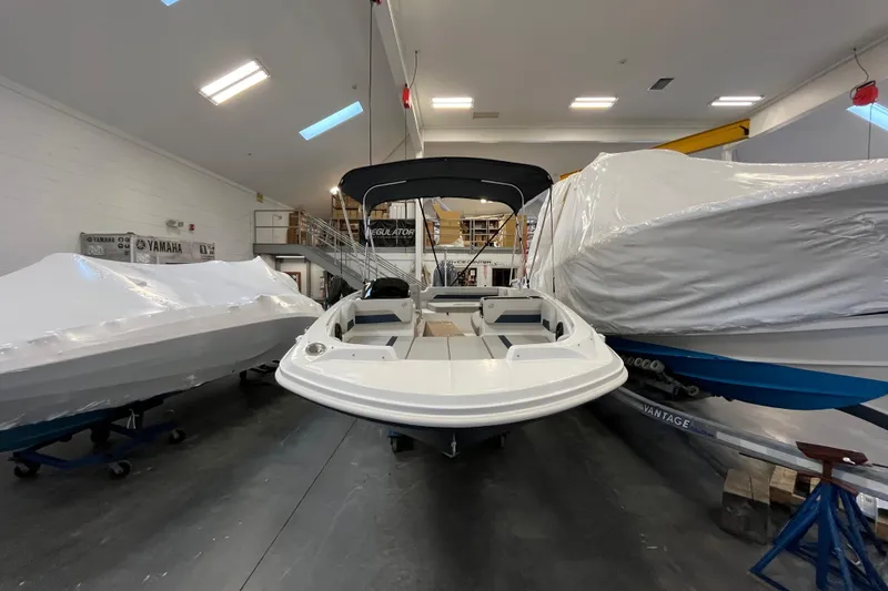 Slide: The Image of 2026 Hurricane SunDeck Sport 185 OB boat in indoor storage, surrounded by covered vessels. - 3