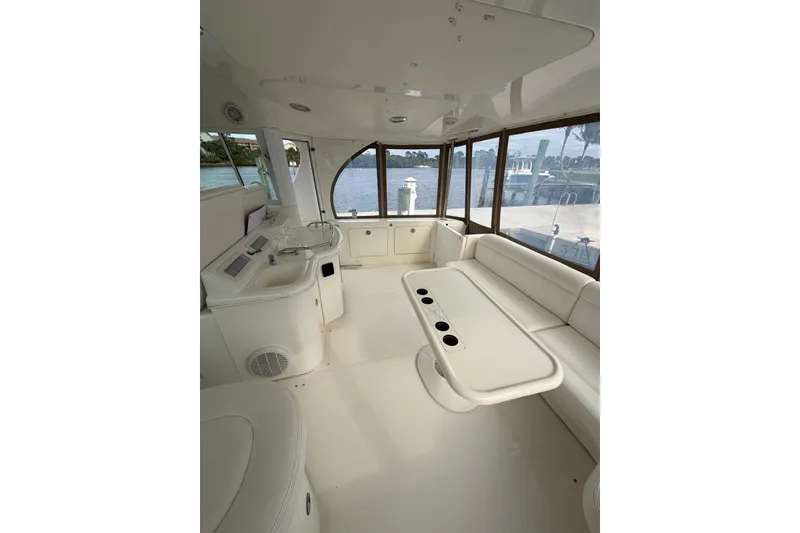 Slide: The Image of 2004 Sea Ray 480 Sedan Bridge interior with white seating and table, overlooking marina. - 11
