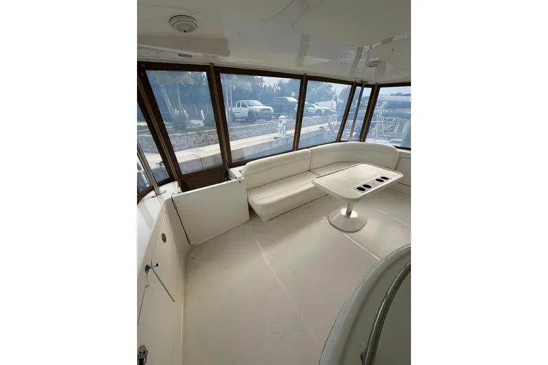 Slide: The Image of 2004 Sea Ray 480 Sedan Bridge interior with white seating and table, dockside view. - 15